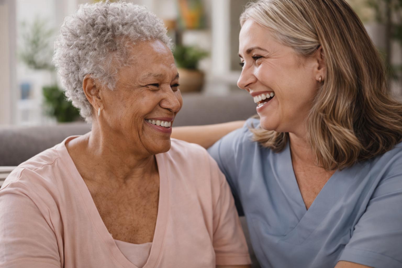 Senior patient laughing with nurse in a home.
